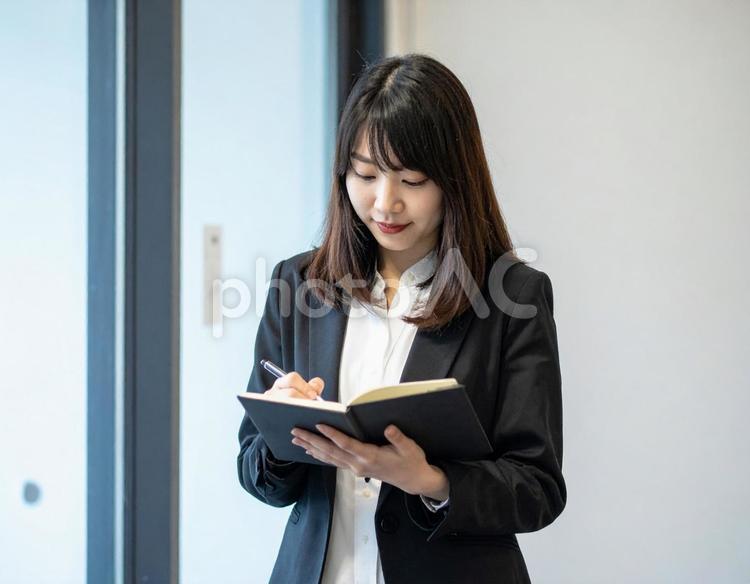 ノートを開きながら歩くビジネスウーマン 女性,ビジネス,ノートの写真素材