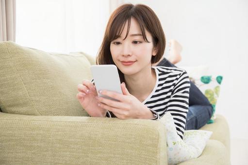 ソファーでスマホを使う女性 ソファーでスマホを使う女性 スマホ,女性,人物の写真素材
