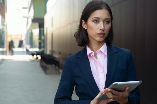 街なかでタブレットを持って立つビジネスウーマン ビジネスウーマン,ビジネス,女性の写真素材