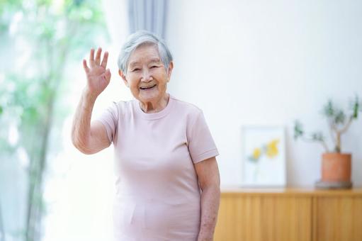 右手を上げる笑顔の高齢女性 女性,手を挙げる,手を振るの写真素材