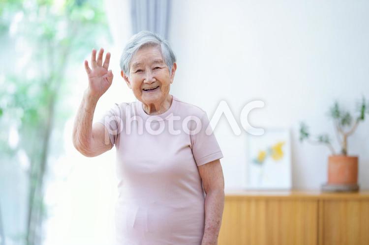 右手を上げる笑顔の高齢女性 女性,手を挙げる,手を振るの写真素材