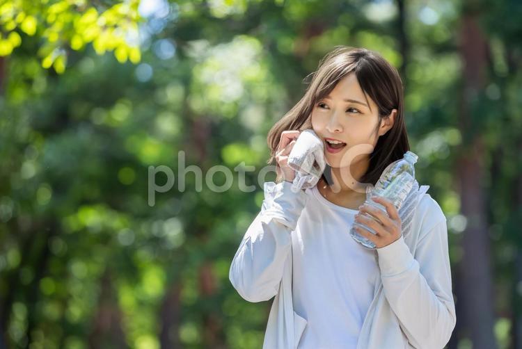 タオルで汗を拭って水分補給する女性 水分補給,有酸素運動,ペットボトルの写真素材