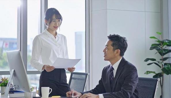 上司に報告する女性社員 上司に報告する女性社員の写真