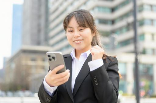 スマホを見て喜ぶ女性 スマホを見て喜ぶ女性 ビジネス,女性,ビジネスウーマンの写真素材
