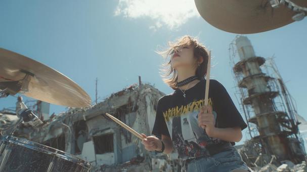 廃工場を背景に力強くドラムを叩く女性 廃工場を背景に力強くドラムを叩く女性の写真