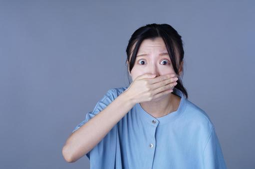 口を片手で覆って驚く青い服の女性 女性,口を覆う,驚くの写真素材