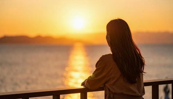 夕暮れの海辺にたたずむ日本人女性 夕暮れの海辺にたたずむ日本人女性の写真