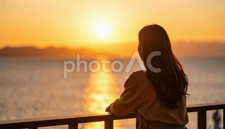 夕暮れの海辺にたたずむ日本人女性 夕焼け,夏,光の写真素材