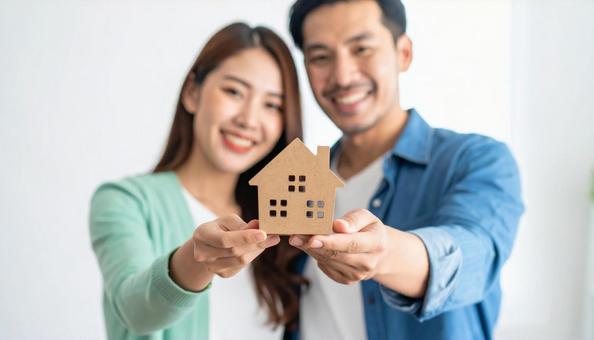 住宅模型を持つ若い日本人夫婦の写真