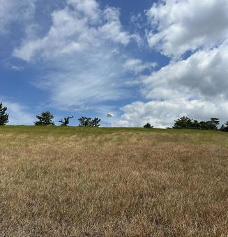 夏の小高い丘に立つゴルフのの一本の白い旗の写真