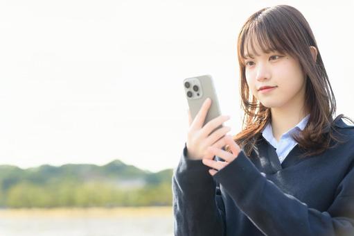 スマホを操作する女子高生 スマホを操作する女子高生 女子高生,電話,登校の写真素材