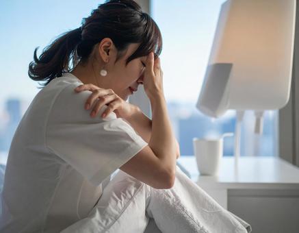 部屋でうつ病・体調不良に悩む日本人女性の写真