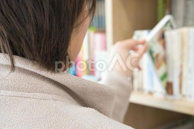 本棚から好みの本を選ぶ女性 本,本棚,選ぶの写真素材