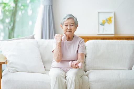 真剣な顔で両手にダンベルを持つ高齢女性 女性,ダンベル,持つの写真素材