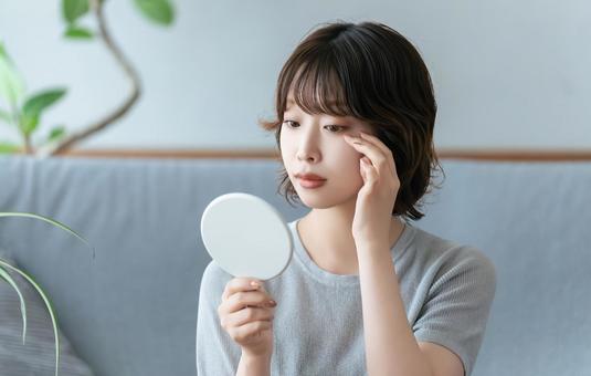 鏡で目元をチェックする女性 女性,美容,健康の写真素材