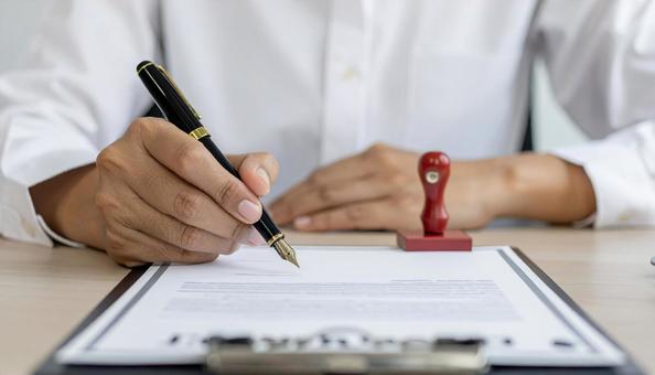 契約書に万年筆でサインをする男性の手 契約書に万年筆でサインをする男性の手の写真