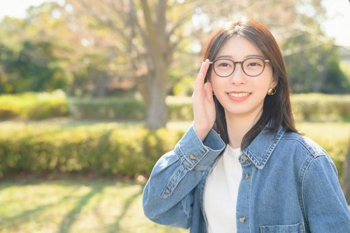 公園で微笑むメガネの女性 公園で微笑むメガネの女性の写真