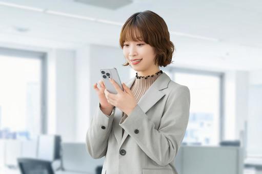 スマホを使う笑顔の女性・ビジネスウーマン 女性,スマホ,スマートフォンの写真素材