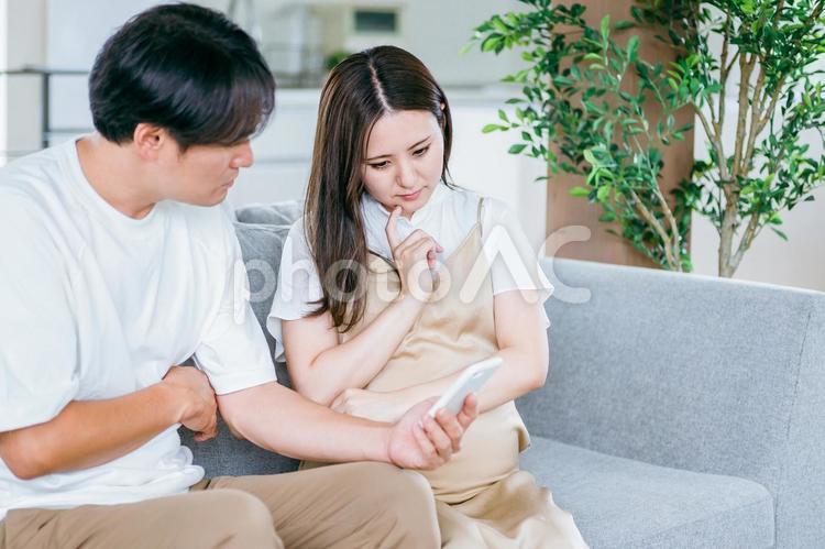 スマホを見る妊婦と男性（悩む） 妊婦,妊娠,夫婦の写真素材