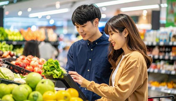 スーパーでセルフレジを使う若い日本人夫婦 スーパーでセルフレジを使う若い日本人夫婦の写真