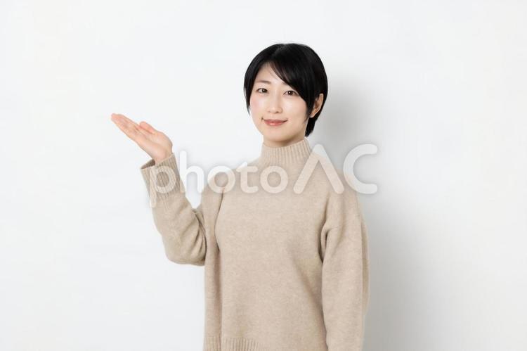 片手を上げて案内をしている笑顔の女性 女性,女子,女の写真素材