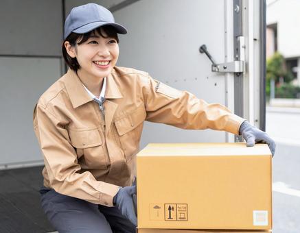 トラックから荷物を出す宅配女性ドライバー トラックから荷物を出す宅配女性ドライバーの写真