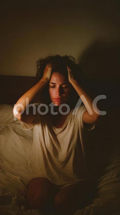 ストレスと戦う女性のリアルな表情 女性,ベッド,部屋の写真素材
