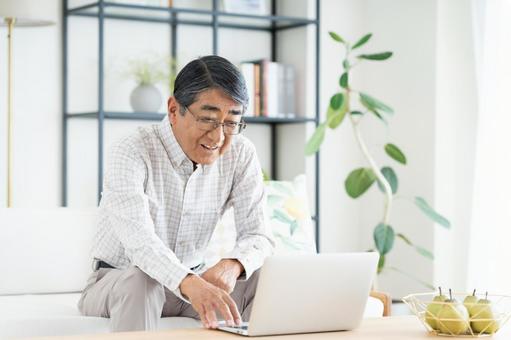 リビングでパソコンを使うシニアの男性 リビングでパソコンを使うシニアの男性 パソコン,シニア,男性の写真素材