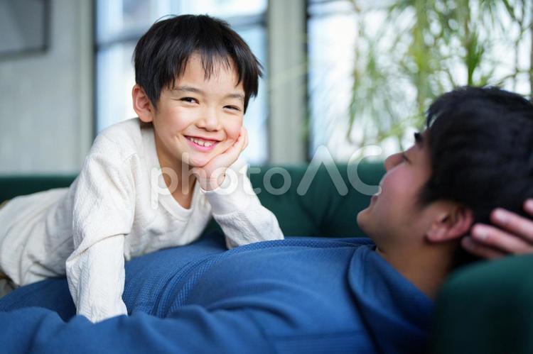 寝転ぶ男性とカメラ目線の男の子 親子,男の子,小学生の写真素材