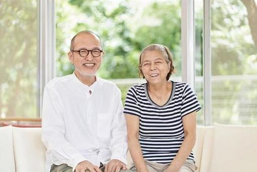 Elderly couple sitting on the couch with a smile Elderly couple sitting on the couch with a smile