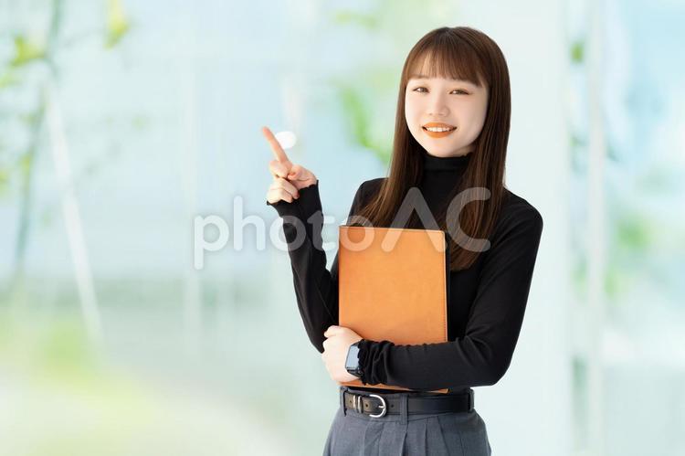 人差し指を立てて案内する笑顔の女性 女性,笑顔,指の写真素材