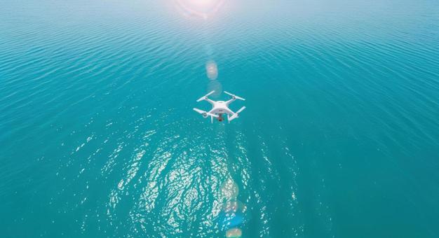 白いドローンが美しい海を飛行する風景 白いドローンが美しい海を飛行する風景の写真