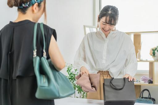 紙袋に洋服を入れるアパレルショップの店員 紙袋に洋服を入れるアパレルショップの店員 店員,販売員,女性の写真素材