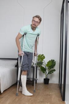 A man standing beside his bed with crutches, JPG