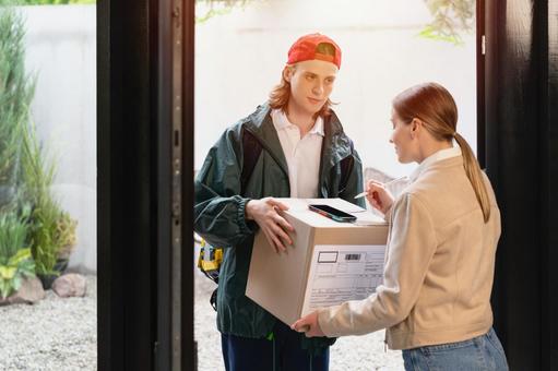玄関で配達物の受取サインをスマートフォンにする 配達,デリバリー,配送の写真素材