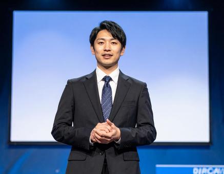 ステージ上で堂々とプレゼンする男性 ステージ上で堂々とプレゼンする男性の写真