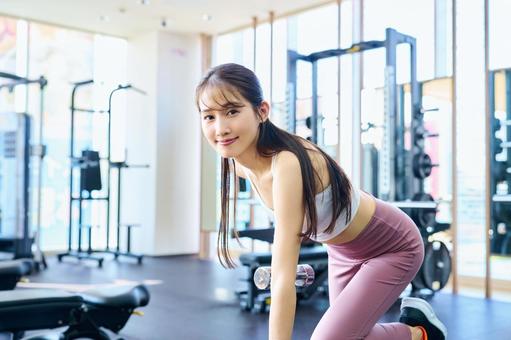 ダンベルで筋トレする笑顔の女性 トレーニング,エクササイズ,フィットネスの写真素材