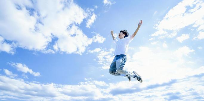 躍動感ある男性のジャンプシーンと青空 躍動感ある男性のジャンプシーンと青空の写真