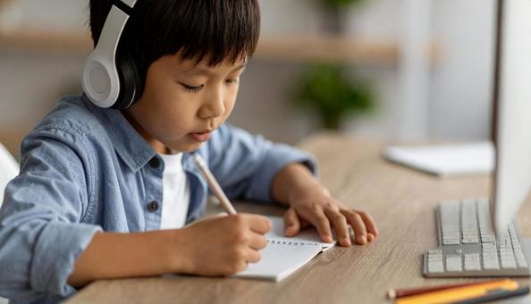 ヘッドフォンをつけてパソコンに向かう子供の写真