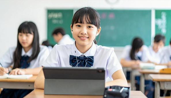 イヤホンをしてタブレットを見る女子学生 イヤホンをしてタブレットを見る女子学生の写真