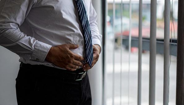 メタボリックなお腹に手を触れる男性 メタボリックなお腹に手を触れる男性の写真