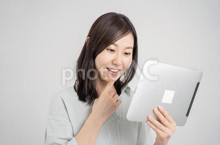 	タブレットを持って喜ぶ女性・白背景 ビジネス,女性,タブレットの写真素材