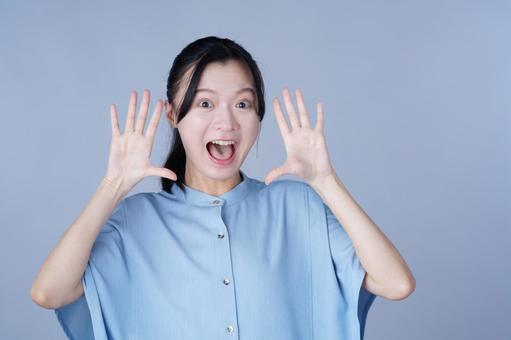 青い服の女性が手を上げてびっくり 女性,驚く,叫ぶの写真素材