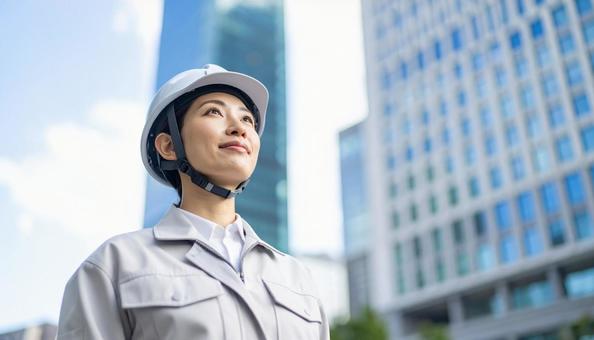 ビル背景に斜め上を見る若い女性建設作業員 ビル背景に斜め上を見る若い女性建設作業員の写真