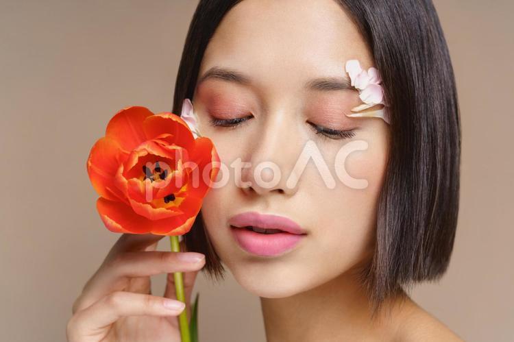 顔に花びらを付け赤い花を持つボブの女性 女性,チューリップ,持つの写真素材