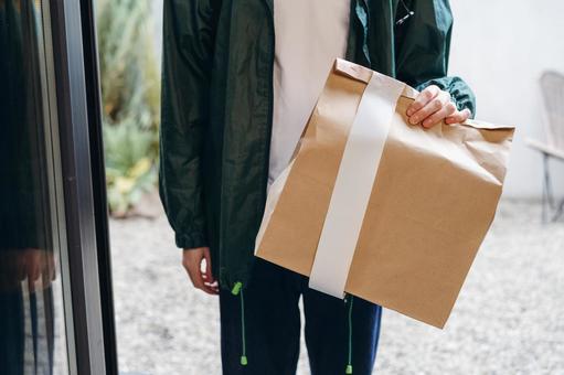玄関に紙袋を届けに来た配達員 配達,フードデリバリー,デリバリーの写真素材