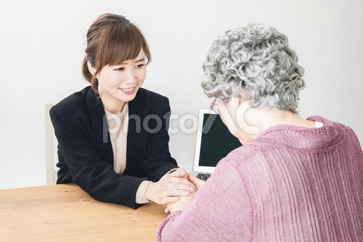 握手するスーツ姿の女性と高齢者 高齢者,慰める,不安の写真素材