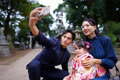 晴れ着の女の子と父親が並んでスマホを構える瞬間 晴れ着の女の子と父親が並んでスマホを構える瞬間 七五三,お参り,七五三参りの写真素材