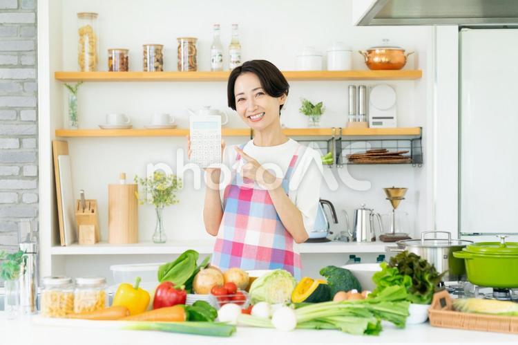 キッチンで電卓を持つミドルの主婦 キッチン,野菜,食費の写真素材