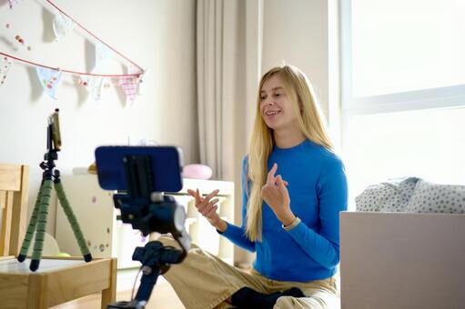 笑顔で動画撮影中の青い服の女性 女性,笑顔,楽しいの写真素材
